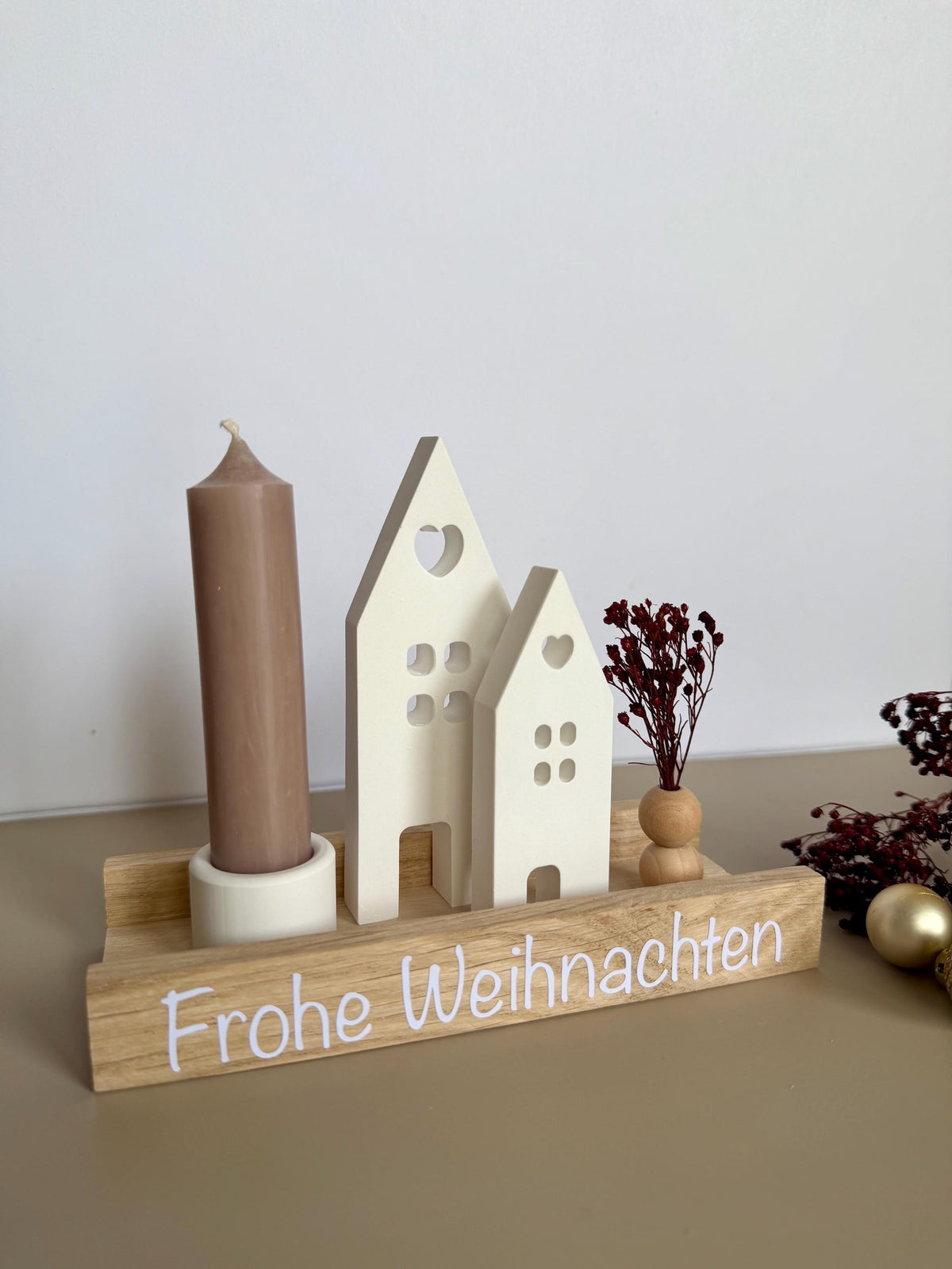 Weihnachtsdorf mit taupefarbener Kerze und Schriftzug Frohe Weihnachten