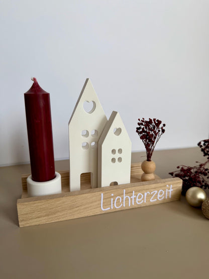 Weihnachtsdorf mit roter Kerze, Häusern und roten Trockenblumen